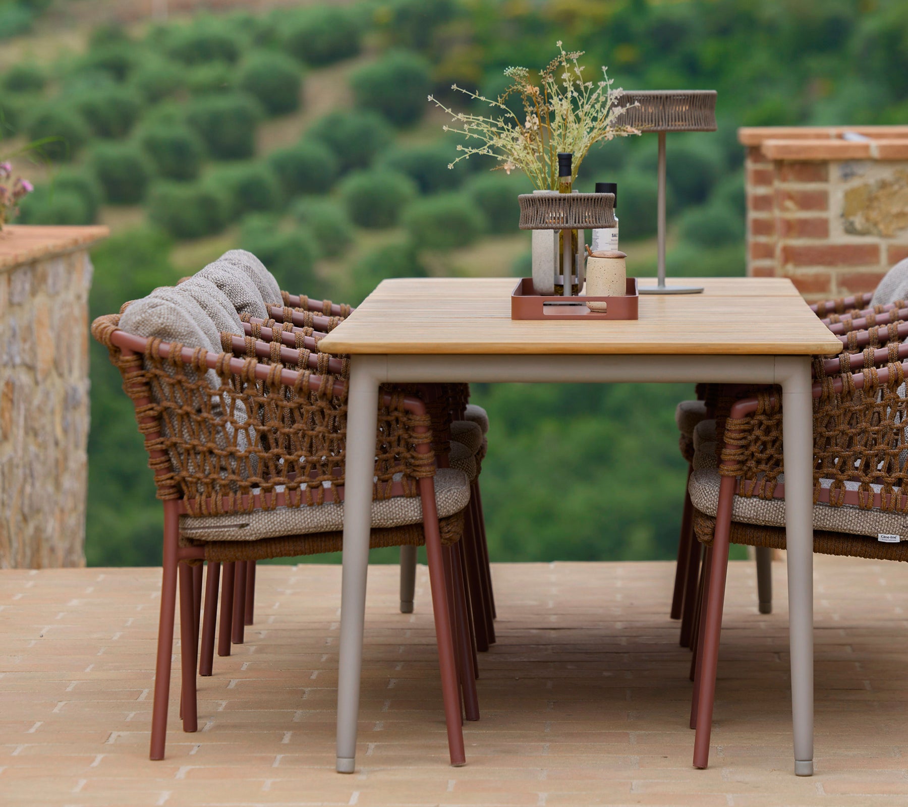 Chaises de salle à manger couleur umber entourant une table élégante, accentuées par un plateau de club et des éléments décoratifs, sur fond de paysage pittoresque.