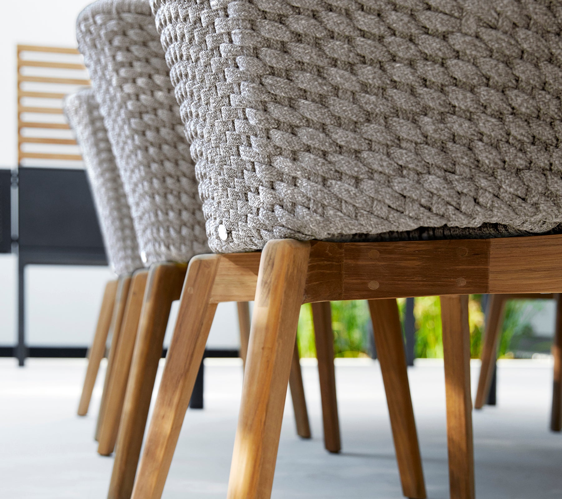 Chaise moderne grise avec un design tissé et des pieds en bois.