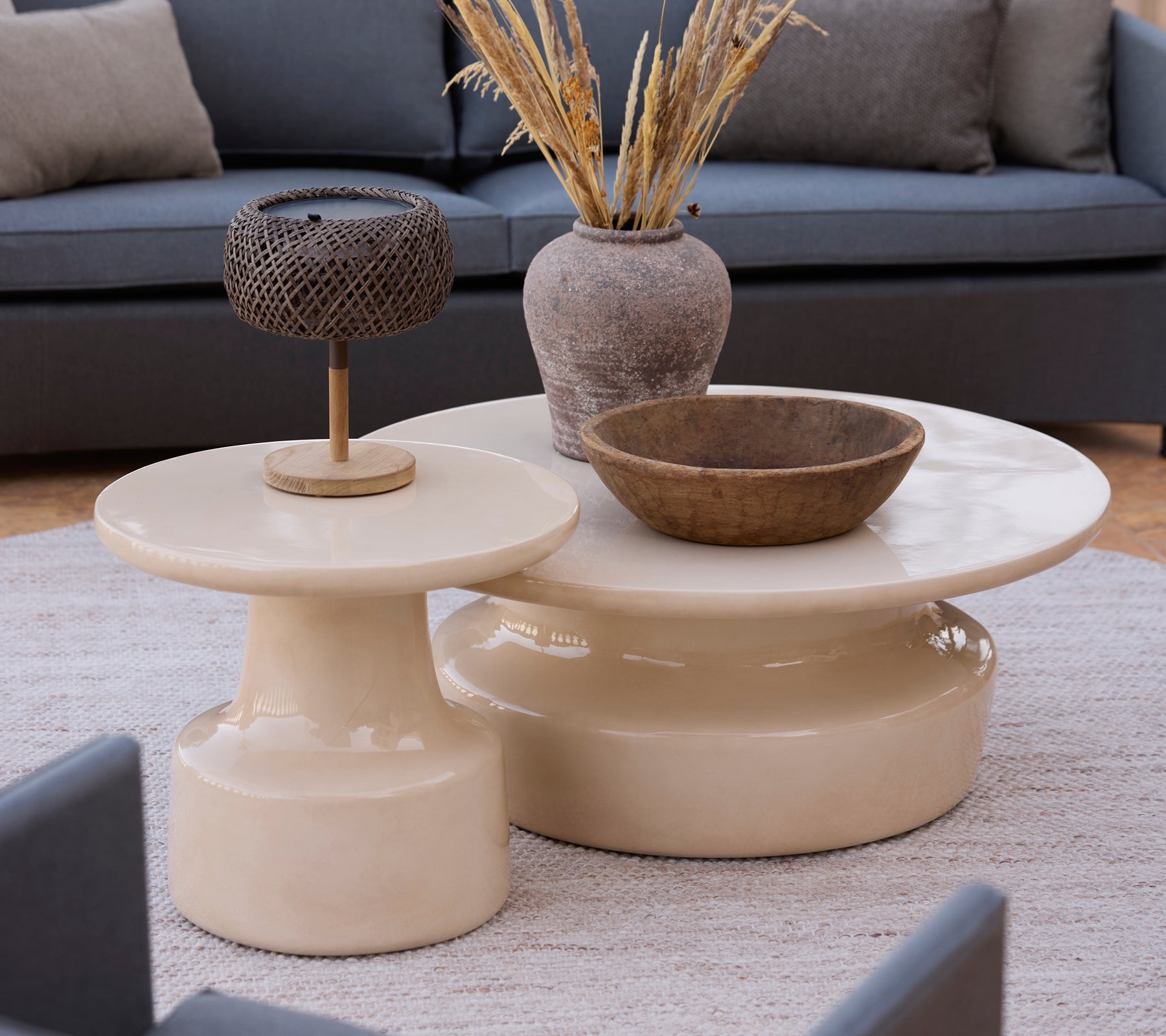 Tables de café et tables d'appoint beige moderne avec un bol marron et une lampe en métal dans un cadre de salon.