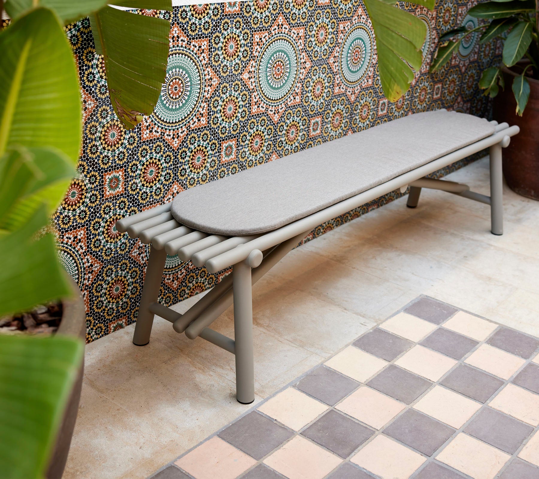 Un banc élégant présentant des éléments de design en forme de bâton, complété par un fond à motifs géométriques et une végétation vibrante.