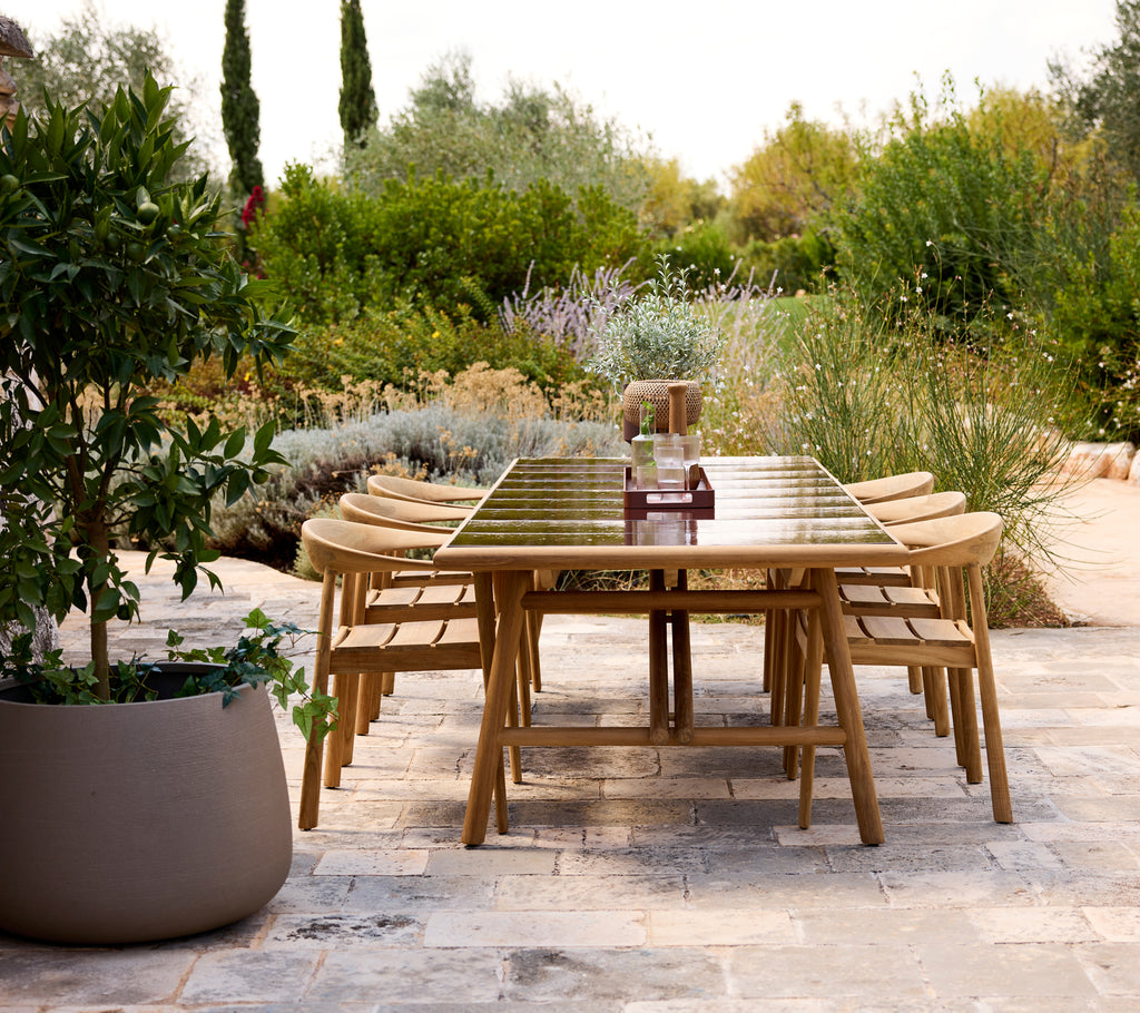 Table à manger moderne en extérieur avec des chaises en bois dans un cadre de jardin.