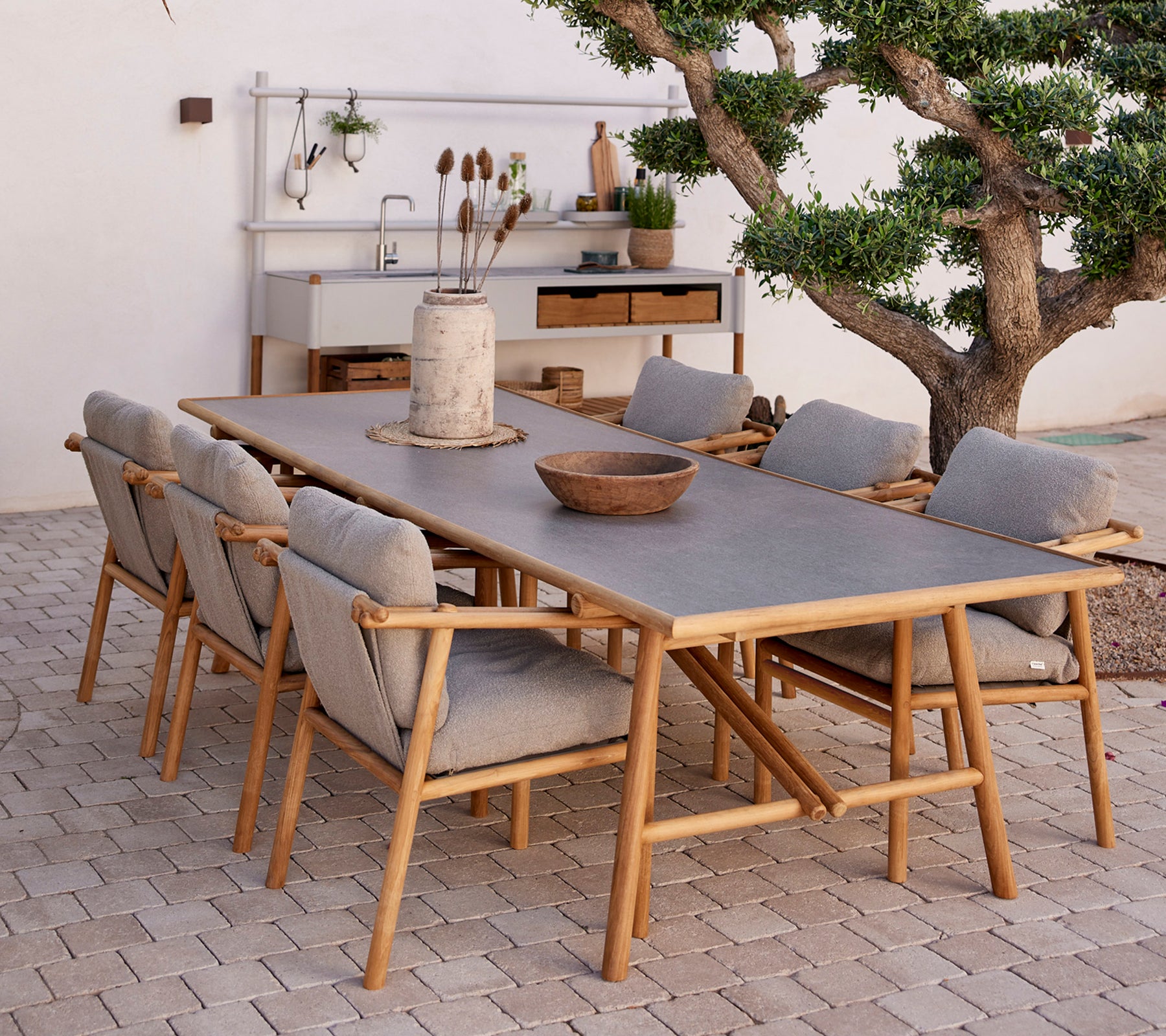 Table à manger en teck entourée de chaises confortables, mettant en valeur des éléments naturels et un style de décor minimaliste.