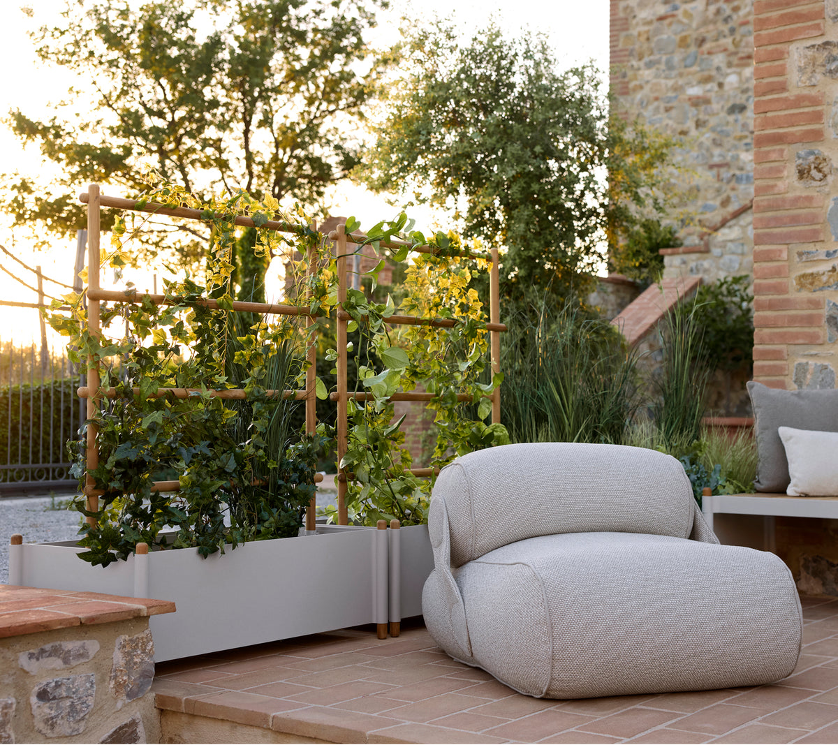Chaise lounge confortable à côté d'un pot de fleurs élégant, avec de la verdure et un cadre extérieur serein éclairé par une lumière naturelle chaleureuse.
