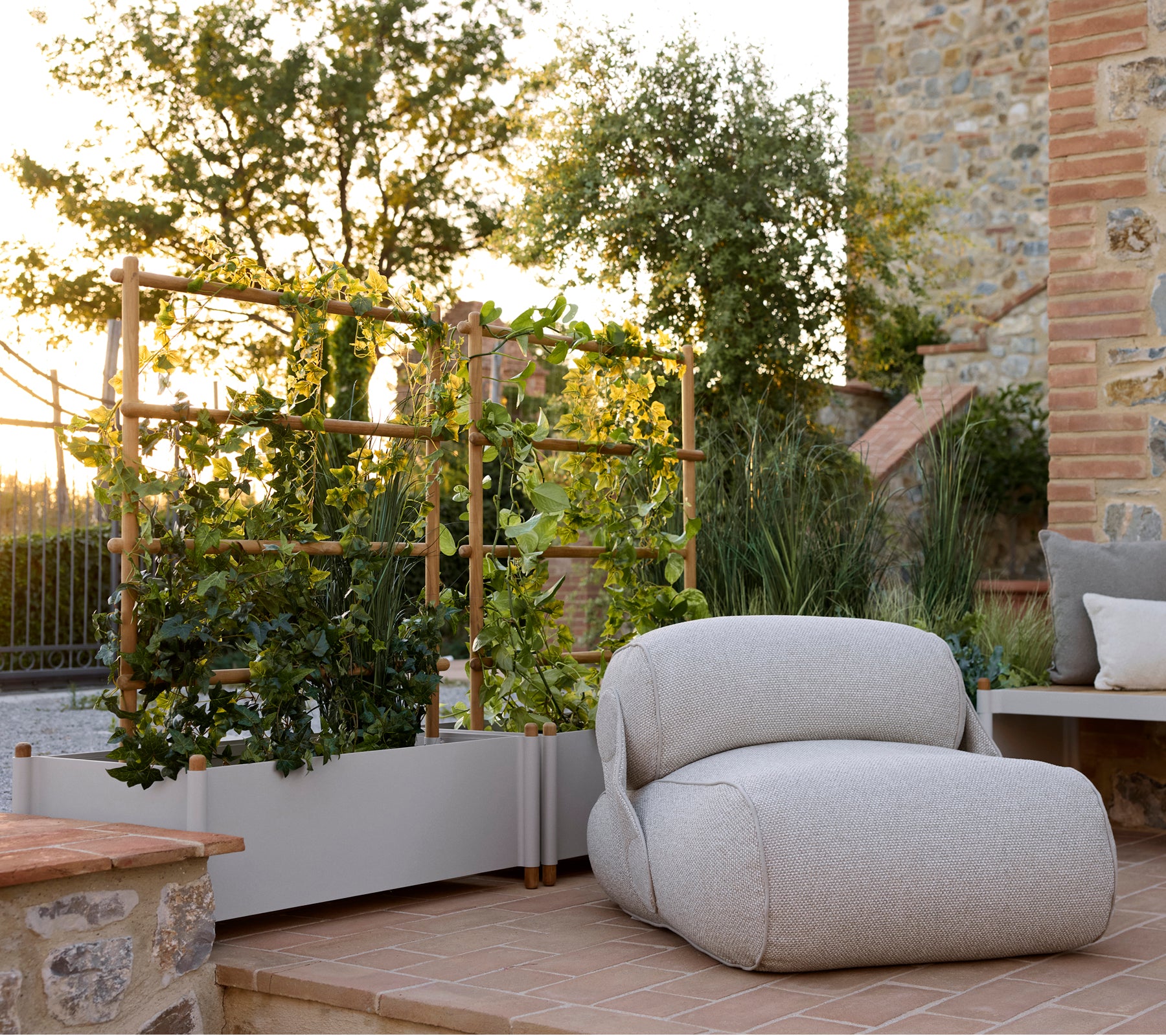 Chaise lounge confortable à côté d'un pot de fleurs élégant, avec de la verdure et un cadre extérieur serein éclairé par une lumière naturelle chaleureuse.