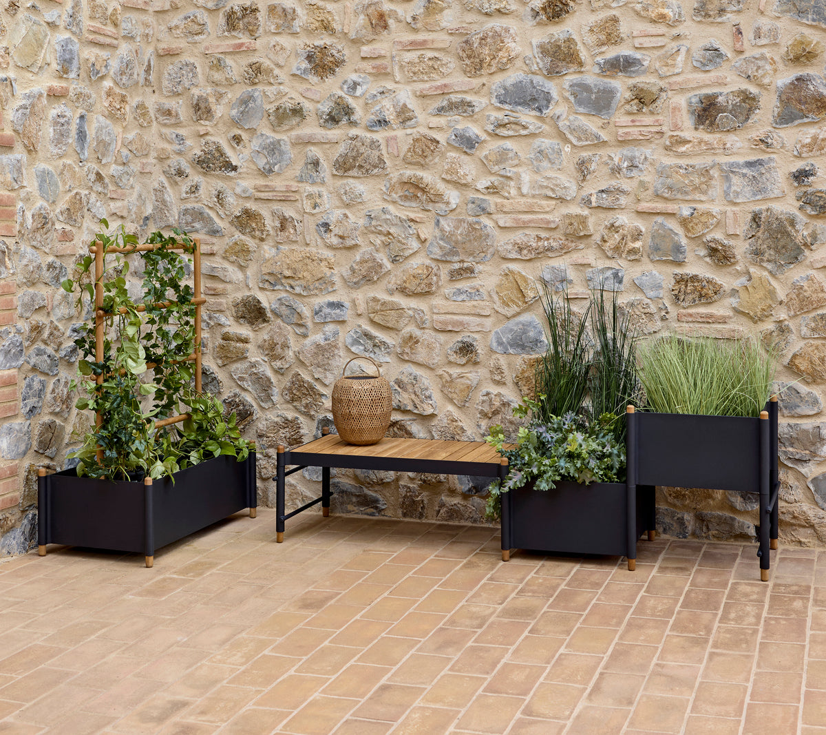Des jardinières élégantes avec une végétation luxuriante et un banc, contre un mur en pierre texturé, enrichissant un espace extérieur serein.