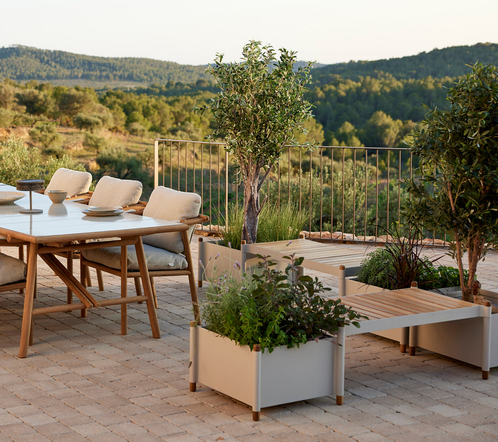 Un espace de vie élégant avec une table, des chaises confortables et des jardinières remplies de verdure, améliorant un paysage serein.