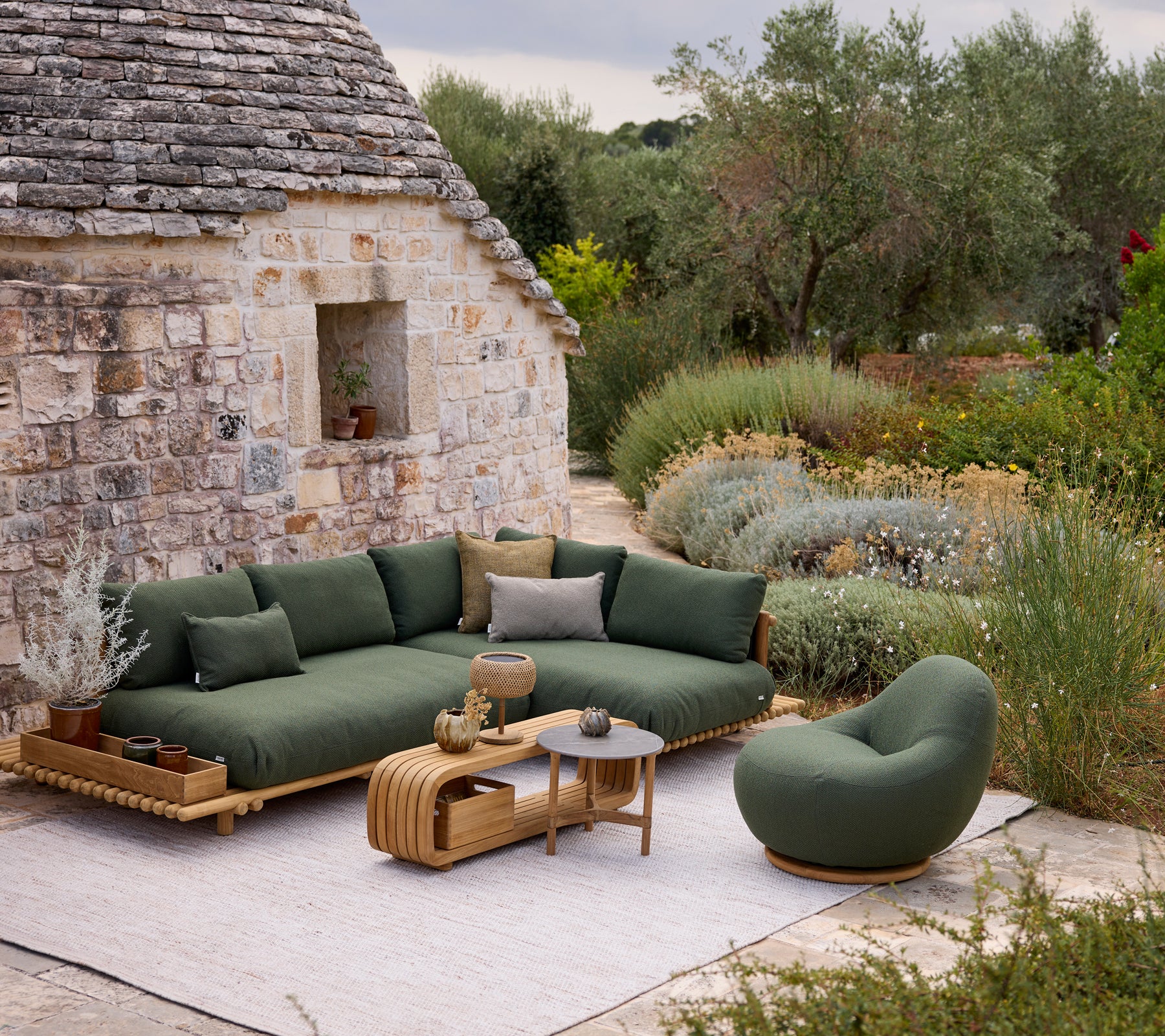 Canapé moderne vert avec une chaise ronde et une table basse dans un cadre de salon extérieur.