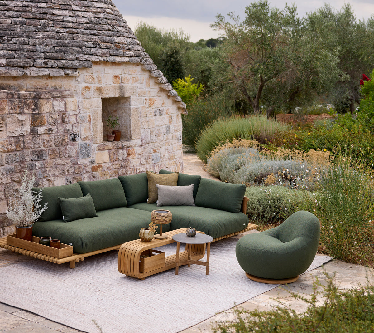 Canapé moderne vert avec une chaise ronde et une table basse dans un cadre de salon extérieur.
