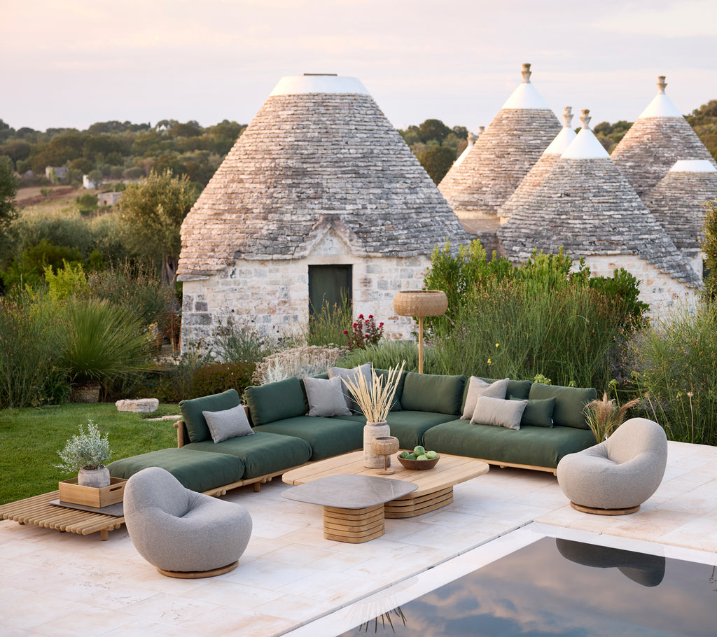 Espace lounge extérieur moderne avec un canapé sectionnel vert, des fauteuils gris et une table basse en bois.