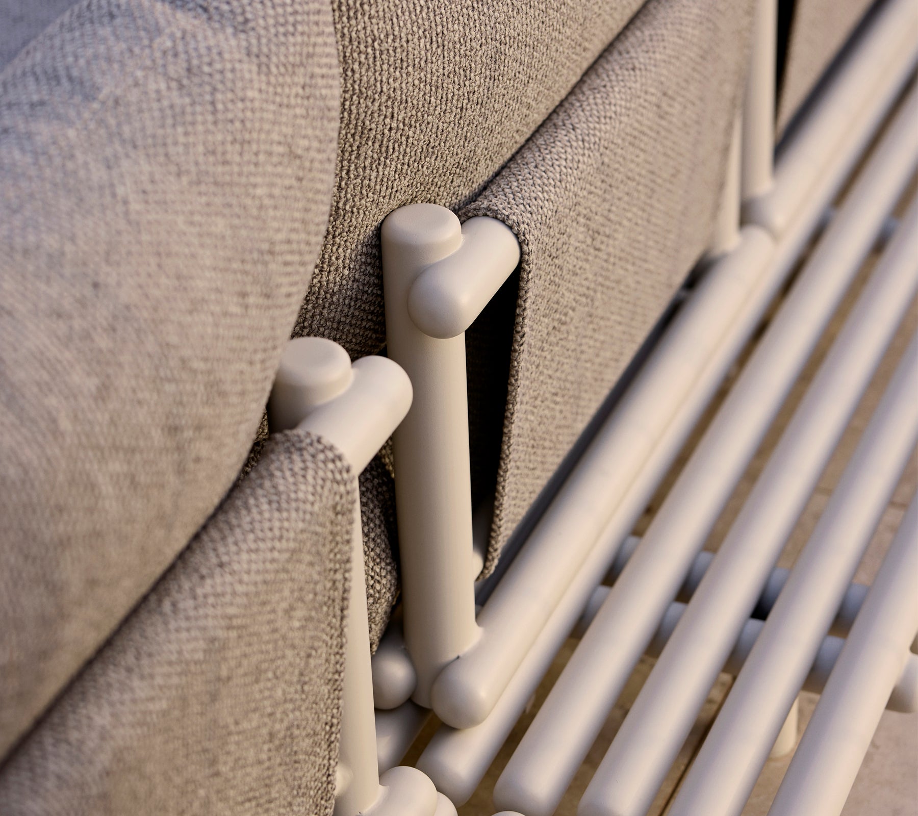 Gros plan d'une plateforme de salon avec des barres en aluminium et un tissu gris texturé, mettant en valeur des éléments de design moderne.