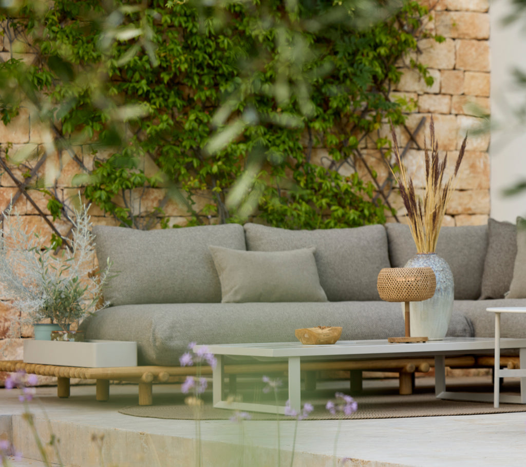 Canapé gris moderne avec une table en bois dans un élégant coin salon extérieur.