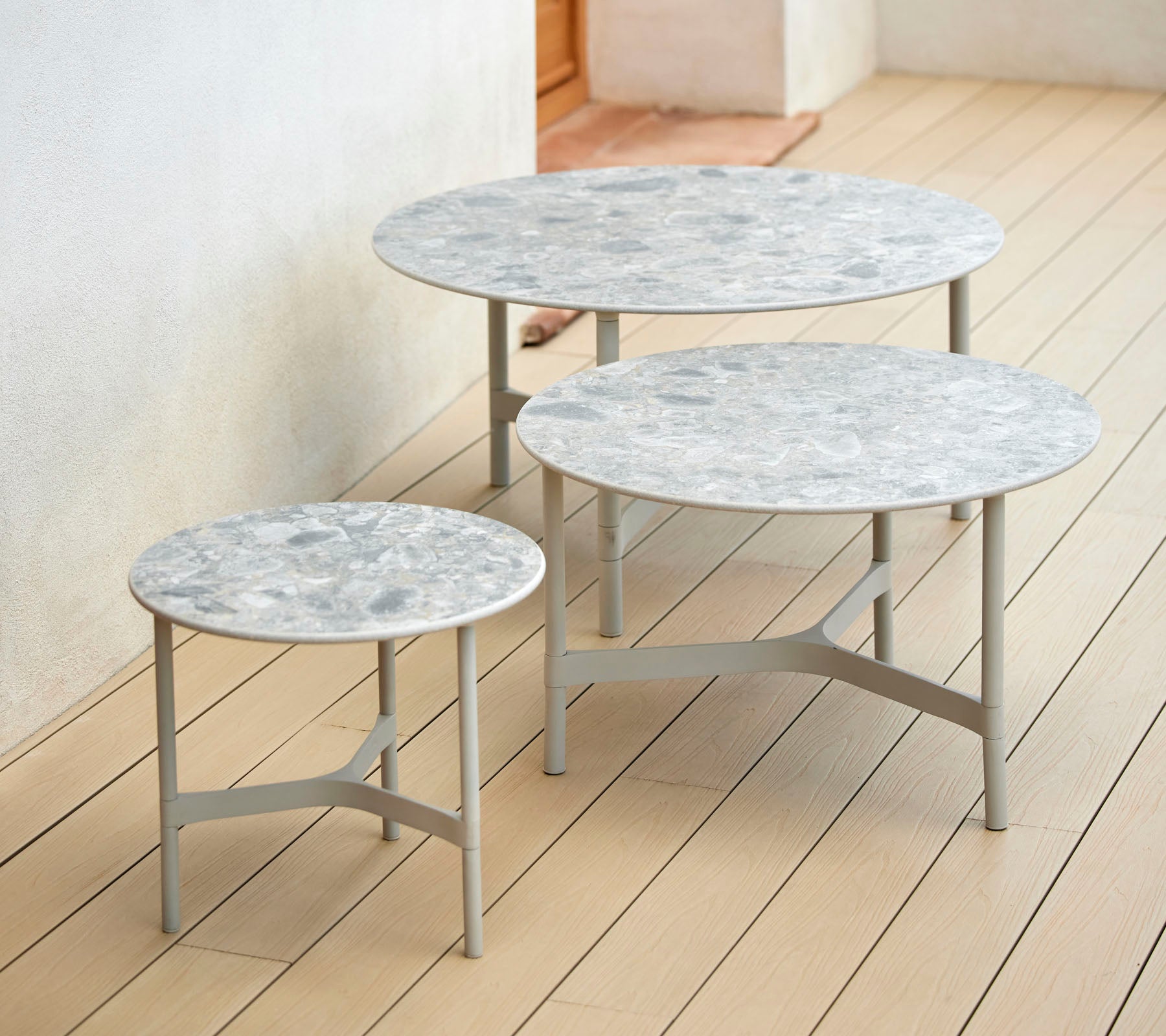 Trois tables rondes de hauteurs variées avec des dessus en marbre et des bases en métal mince, disposées ensemble pour une présentation élégante.
