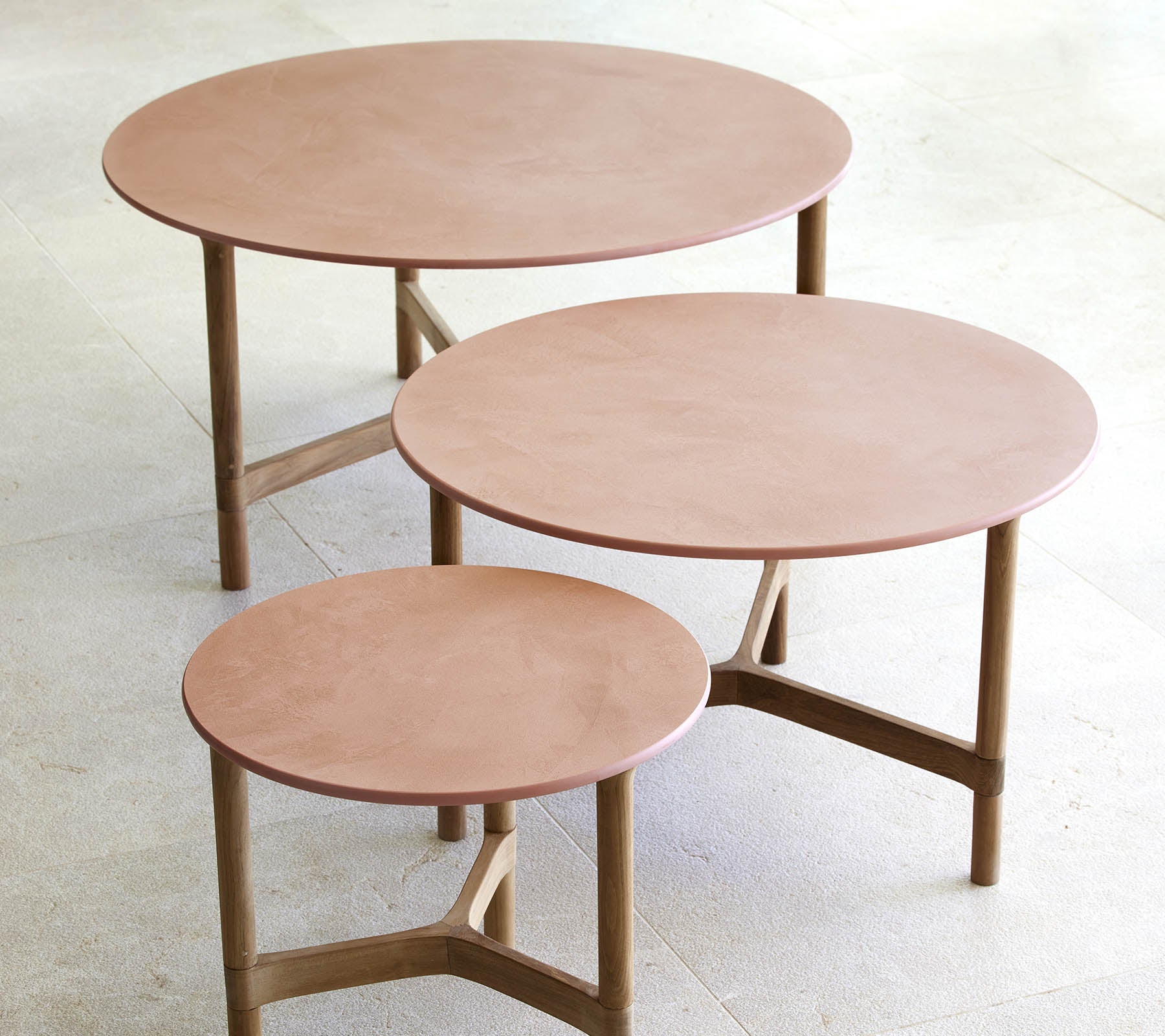 Trois tables basses rondes de tailles variées, présentant un design minimaliste avec des pieds en bois et une surface lisse et élégante.