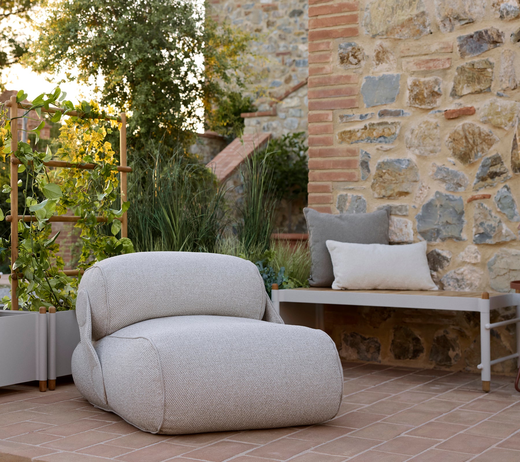 Un fauteuil confortable avec un tissu texturé, accompagné d'un banc à plantes élégante et d'une végétation luxuriante dans un cadre serein.