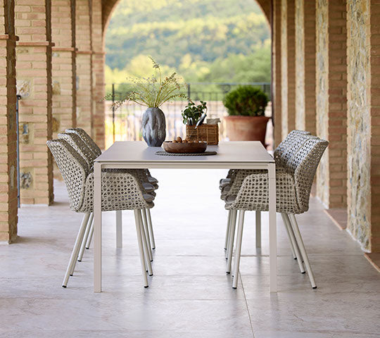 Une installation de salle à manger élégante avec des chaises Vibe et une table Pure dans une douce couleur sable, agrémentée d'éléments décoratifs.