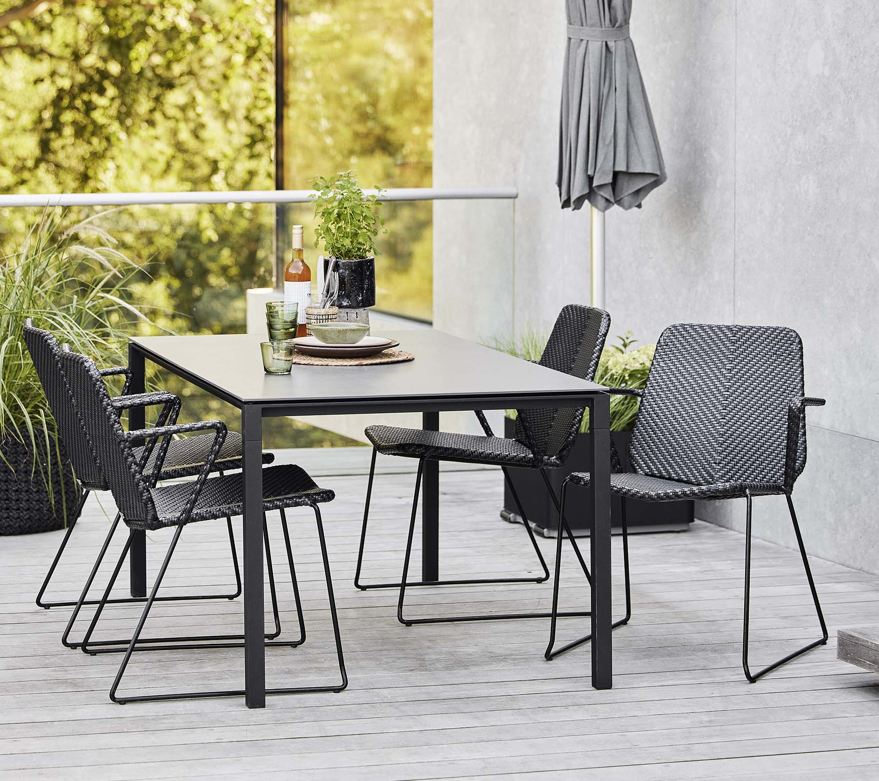 Une table moderne entourée de chaises élégantes, complétée par des objets décoratifs et de la verdure en arrière-plan.