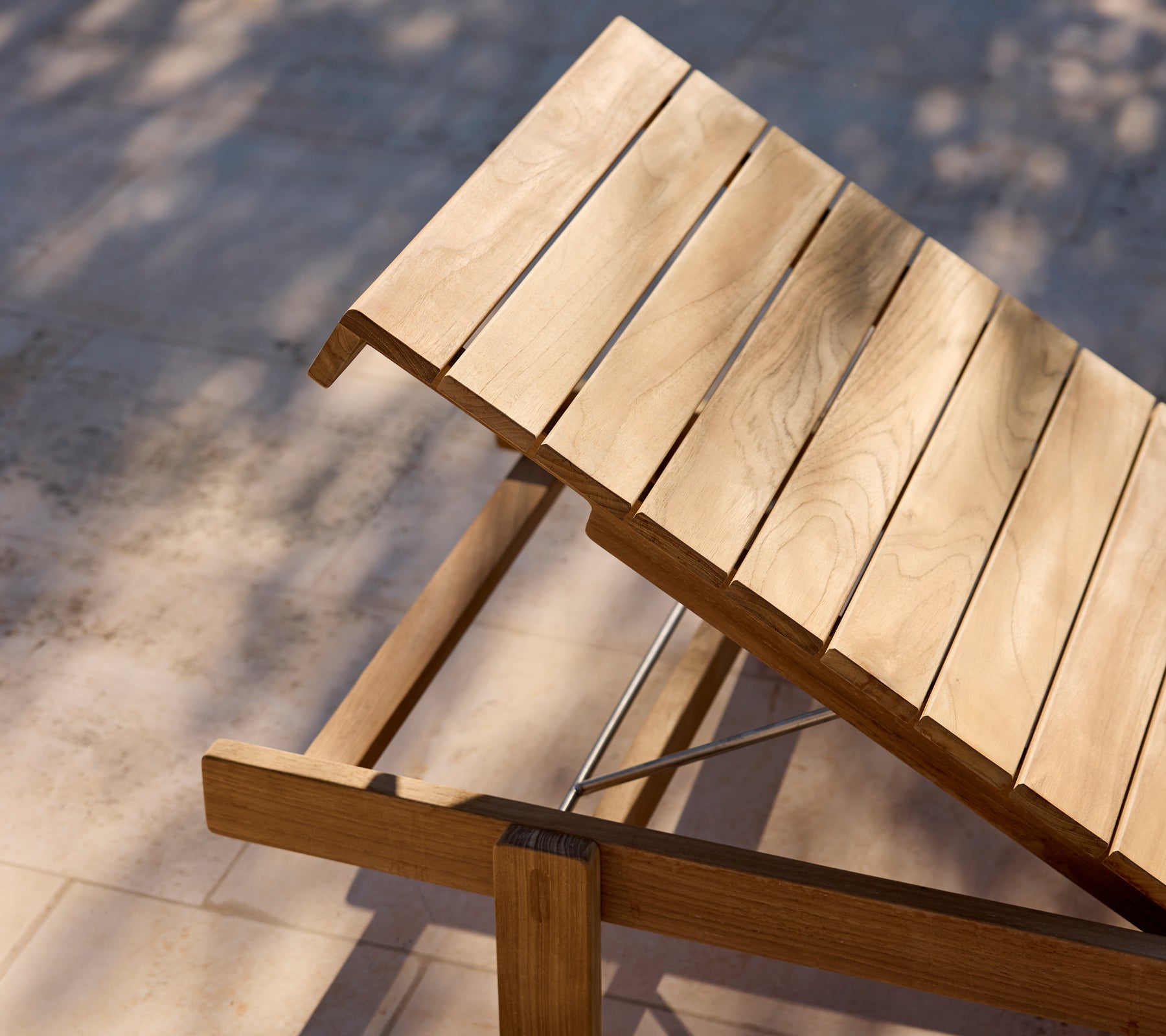 Chaise longue en bois moderne avec dossier ajustable sur un patio ensoleillé.