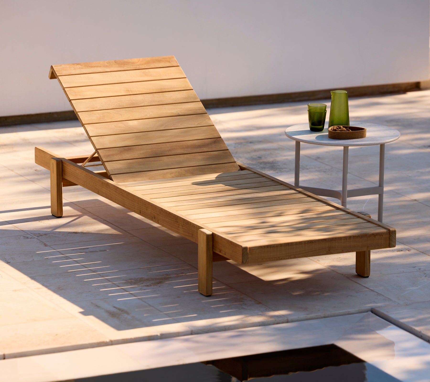 Transat en bois avec une table d'appoint blanche dans un cadre extérieur moderne.