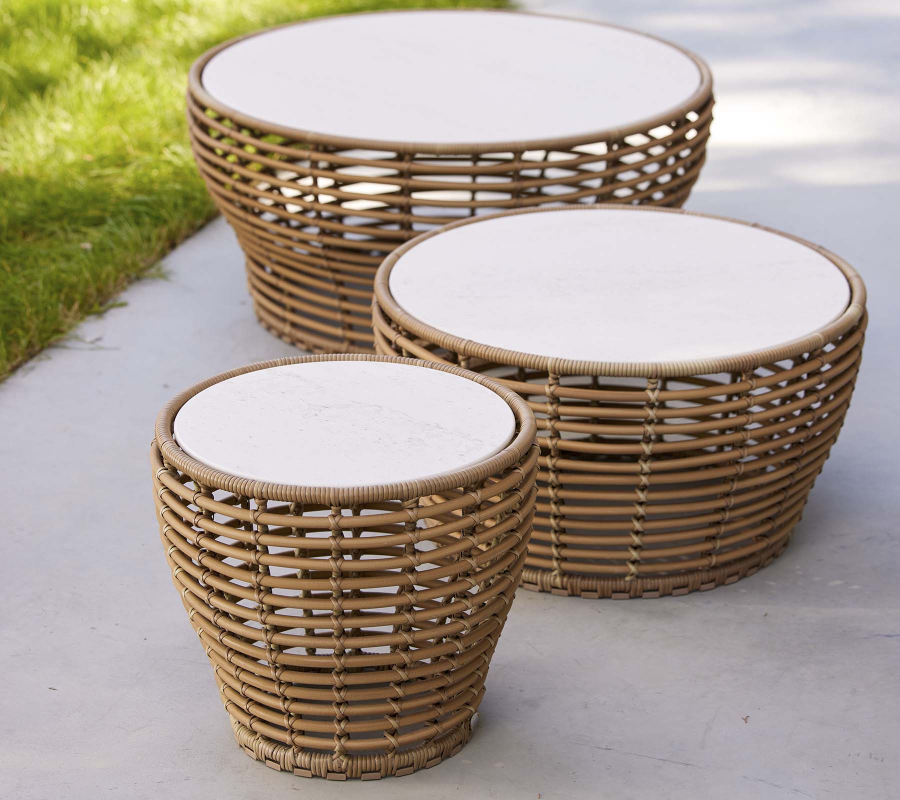 Trois tables basses en osier de différentes tailles, avec des plateaux ronds blancs et un design naturel, idéales pour un espace de vie élégant.