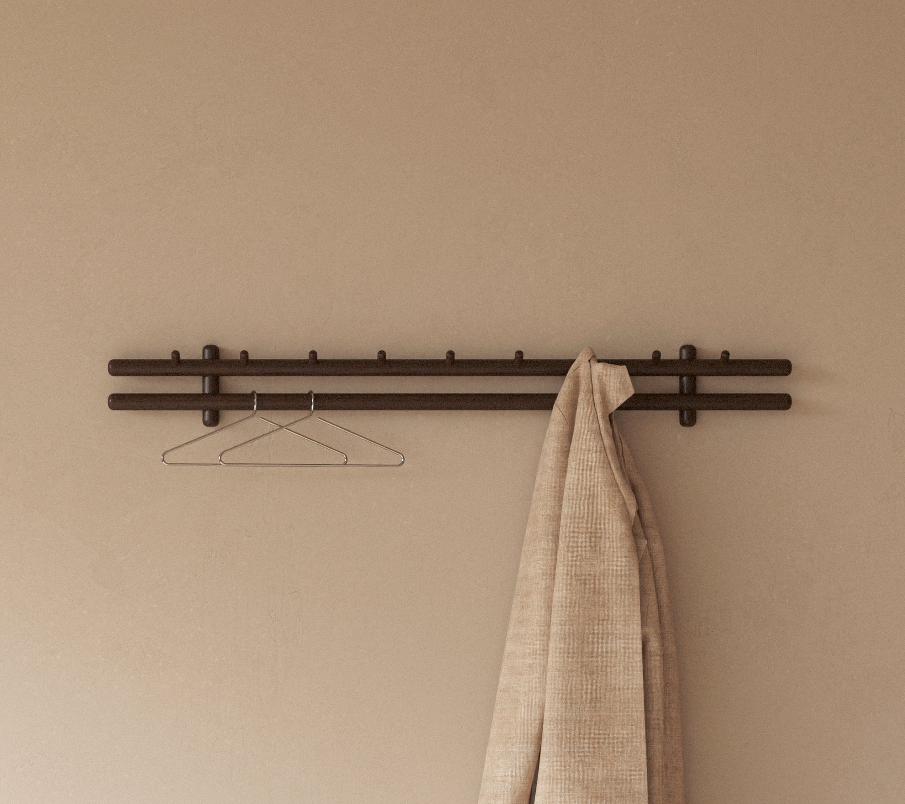 Un porte-manteau avec des bâtons en bois et un crochet, avec un grand chiffon texturé qui pend de celui-ci contre un mur lisse.