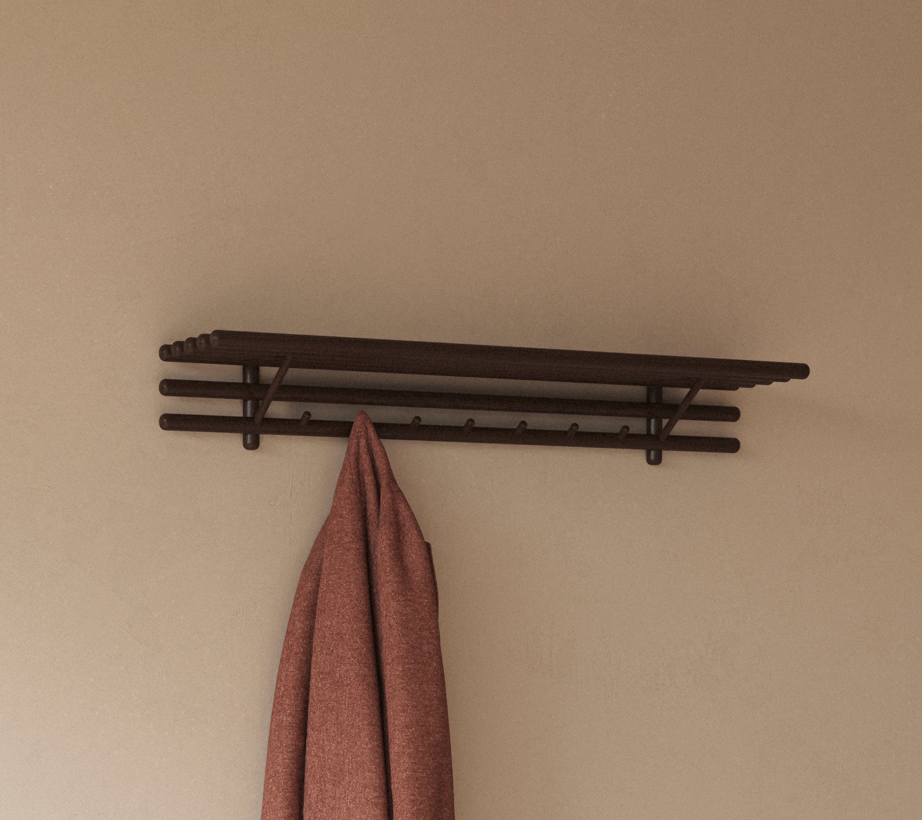 Une étagère minimaliste avec plusieurs crochets tenant un chiffon suspendu, conçu pour un rangement et une organisation pratiques.